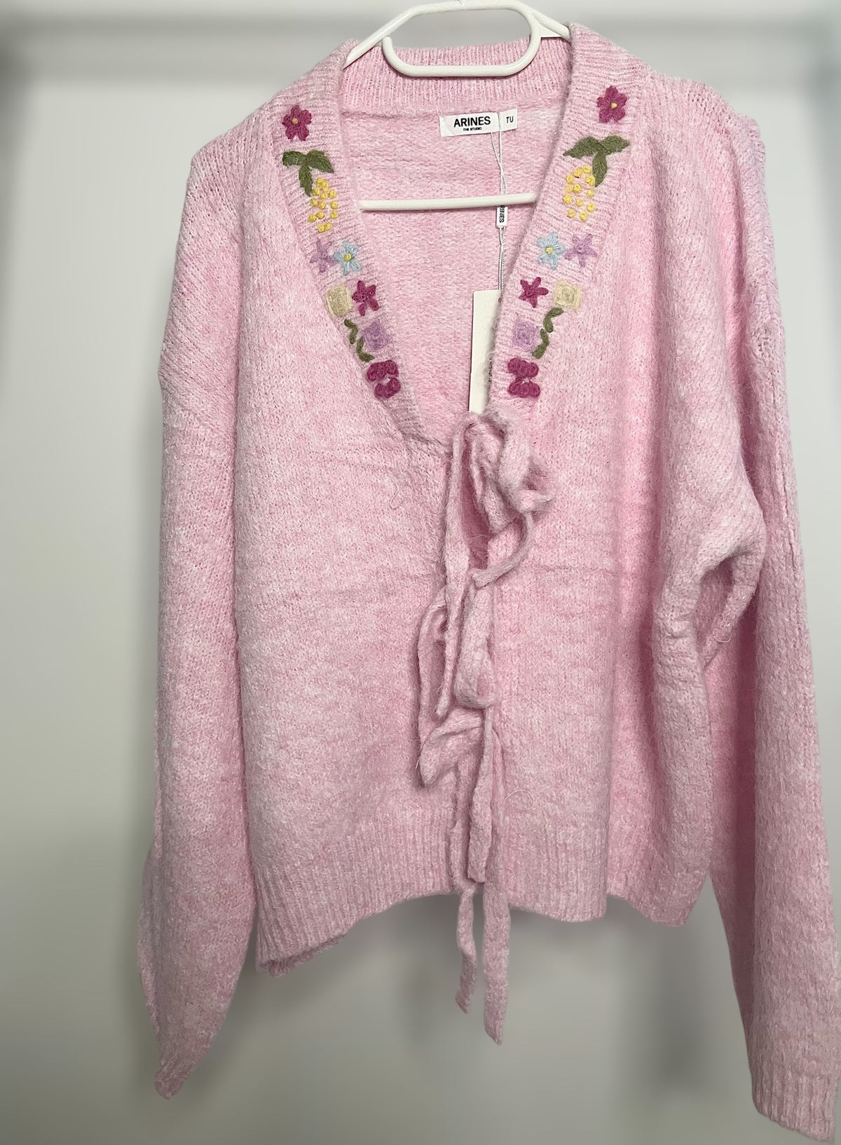 Rosa Strickjacke mit Blumen und Schleifenverschluss